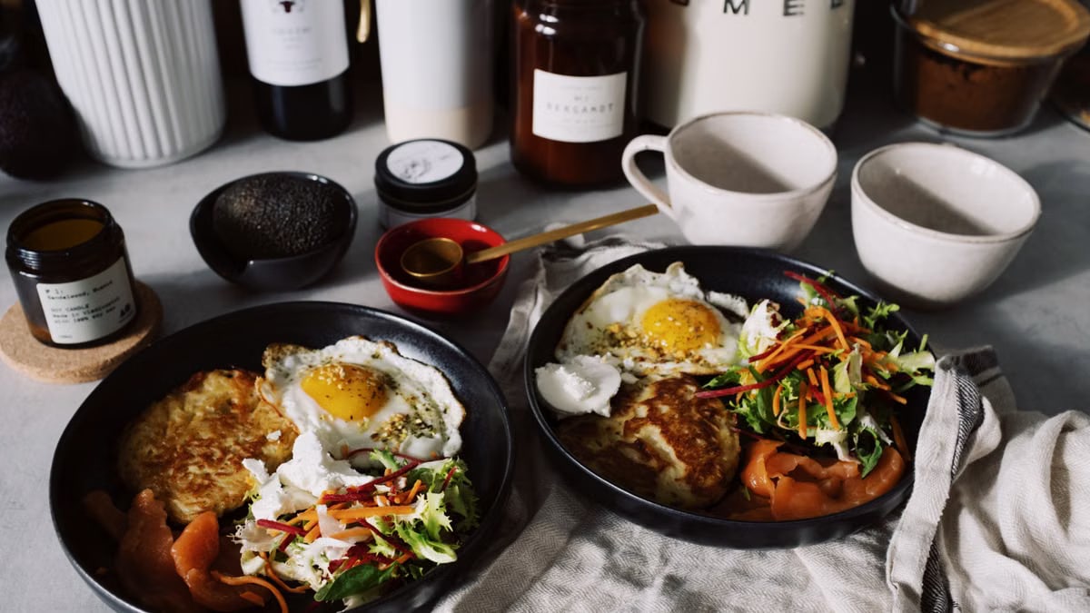 Tasty brunch spread with eggs, salad, and smoked salmon served on black plates.